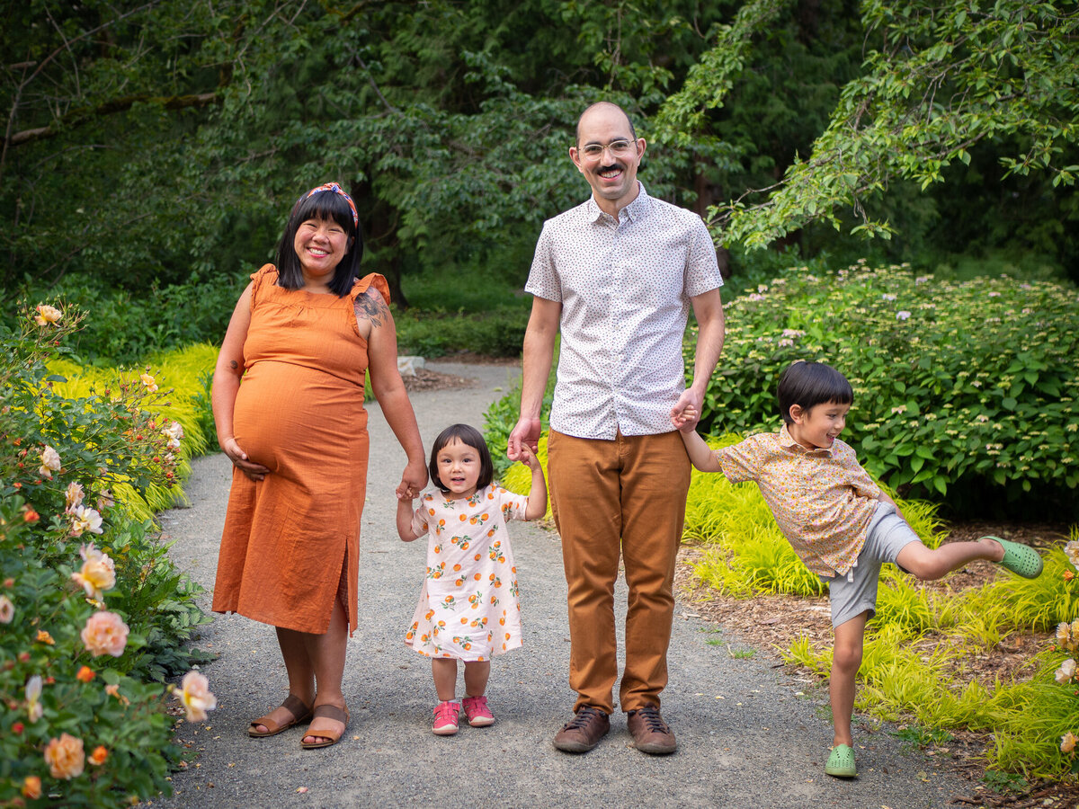 A pregnant mama holds hands with her two children and husband at University of Washington's Botanical Garden.