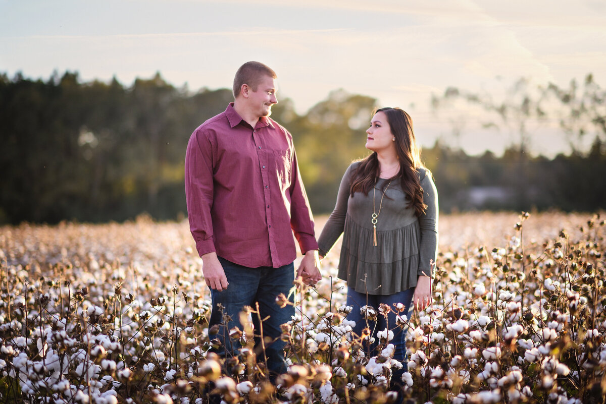 Beautiful Mississippi Engagement Photography: couple holds hands and gazes at each other in Mississippi cotton field