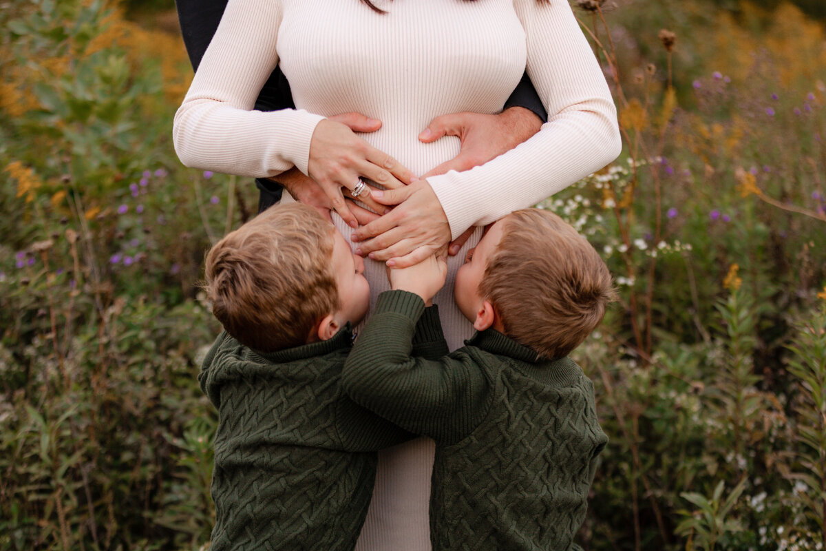 Twin boys kiss their pregnant moms belly.