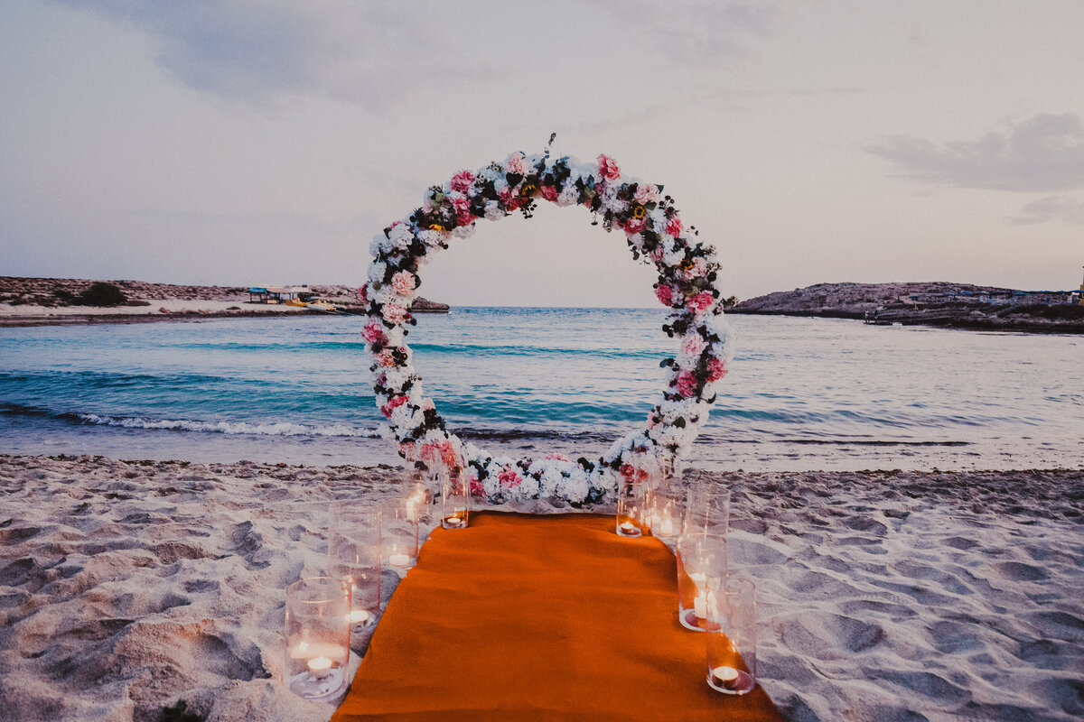 Round Floral Arch  with aisle carpet lined with candles on the sand