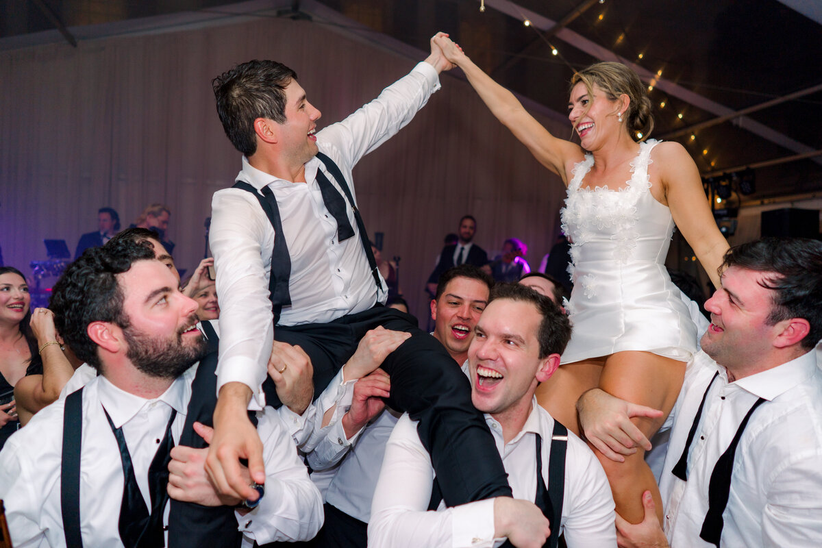 Wedding guests lift up bride and groom. Live band wedding reception at spring Lowndes Grove wedding.