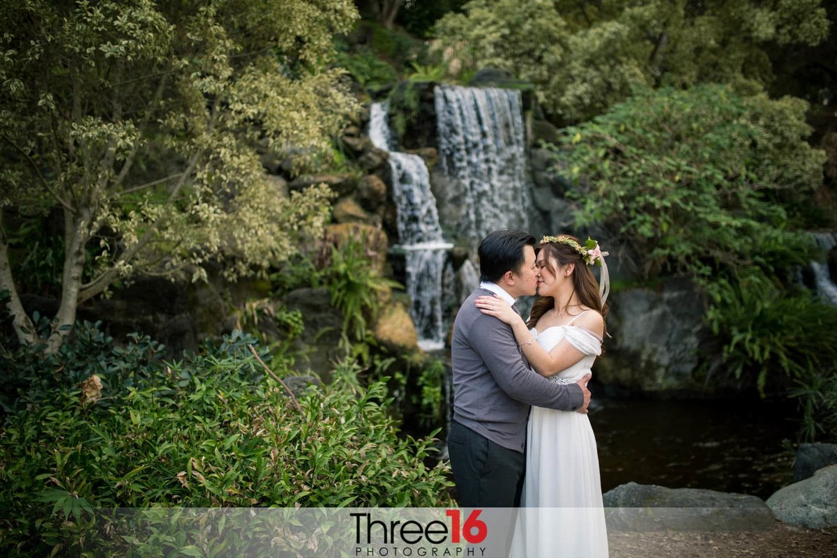 Bride and Groom share an intimate kiss in front of a beautiful waterfall