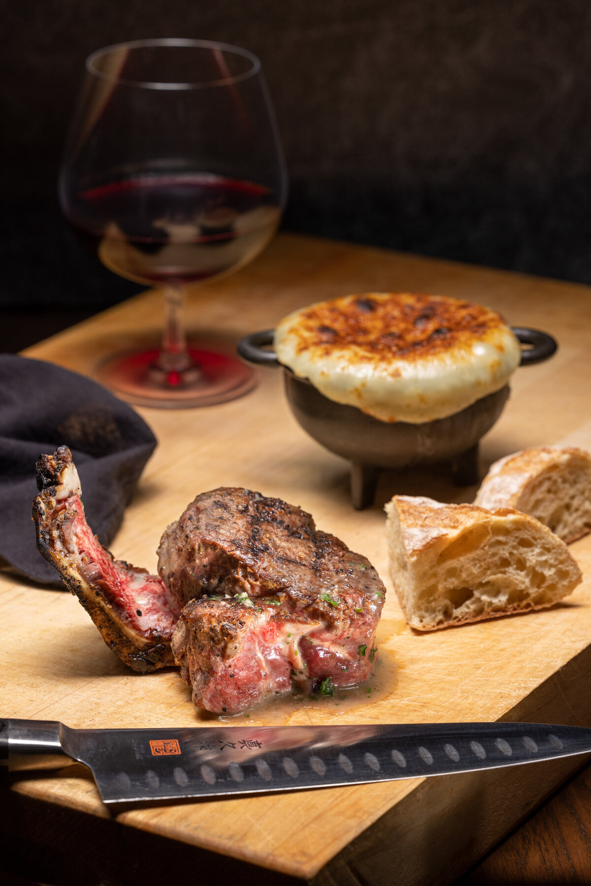 A steak dish with potatoes and a wine glass