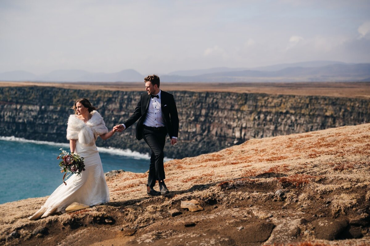 This couple shares a tranquil moment, staring into the distance at the Krisuvikurberg cliffs in Iceland during their elopement, surrounded by the raw beauty of nature.