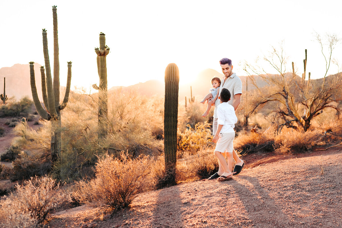 man holding child and looking at other child in the desert
