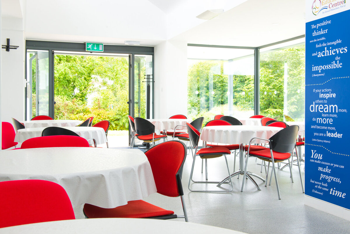 Interior photograph of canteen in office building with red chairs and white tablecloths