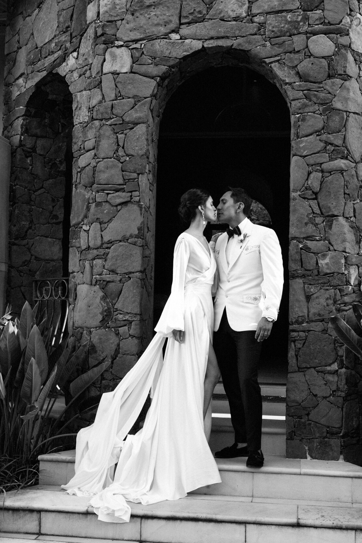 Bride and groom on steps, bride wearing long, flowing, silk modern bridal gown