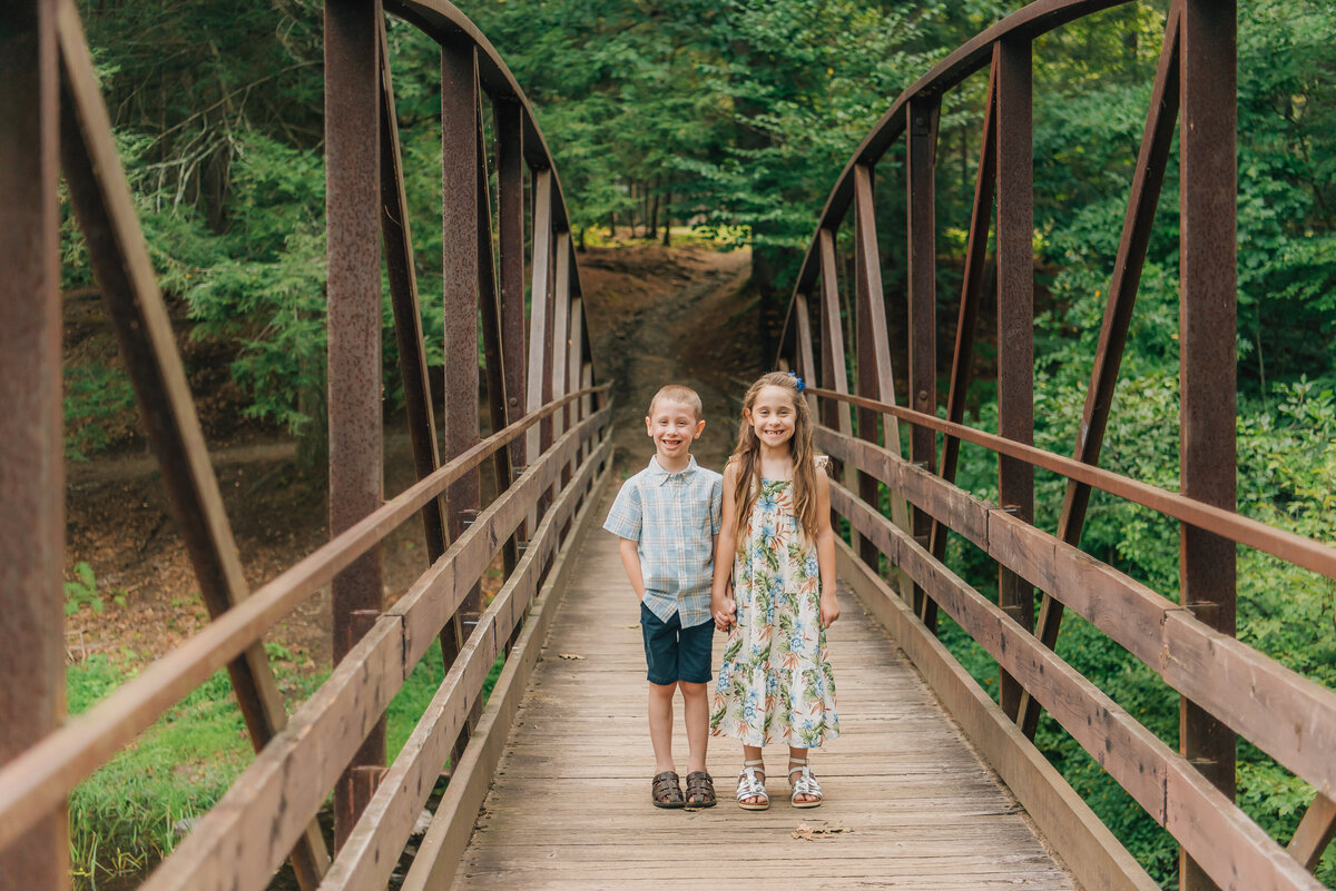 Brother and sister holding hands on bridge