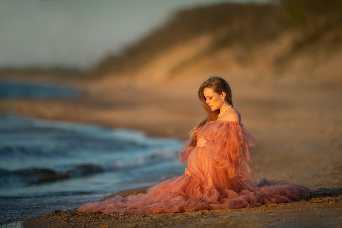 Pregnancy photoshoot of soon to be mother in pink maternity dress at the Indiana dunes National park beach
