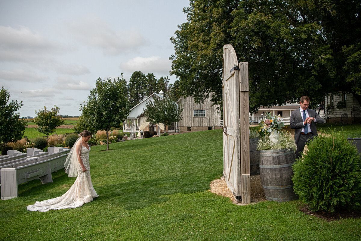 Bride and groom wait on either side of a barn door to do first look.