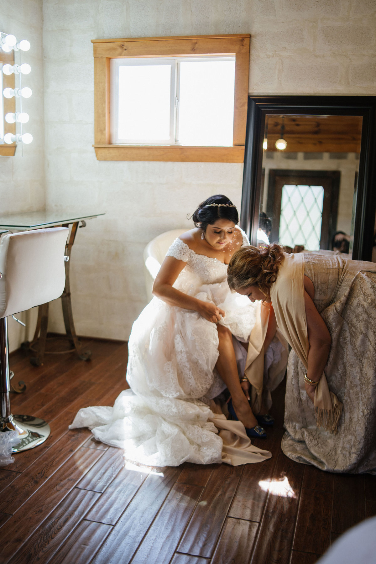 Mother of bride helping daughter put on her wedding shoes during getting ready for ceremony at Oaks of Heavenly venue
