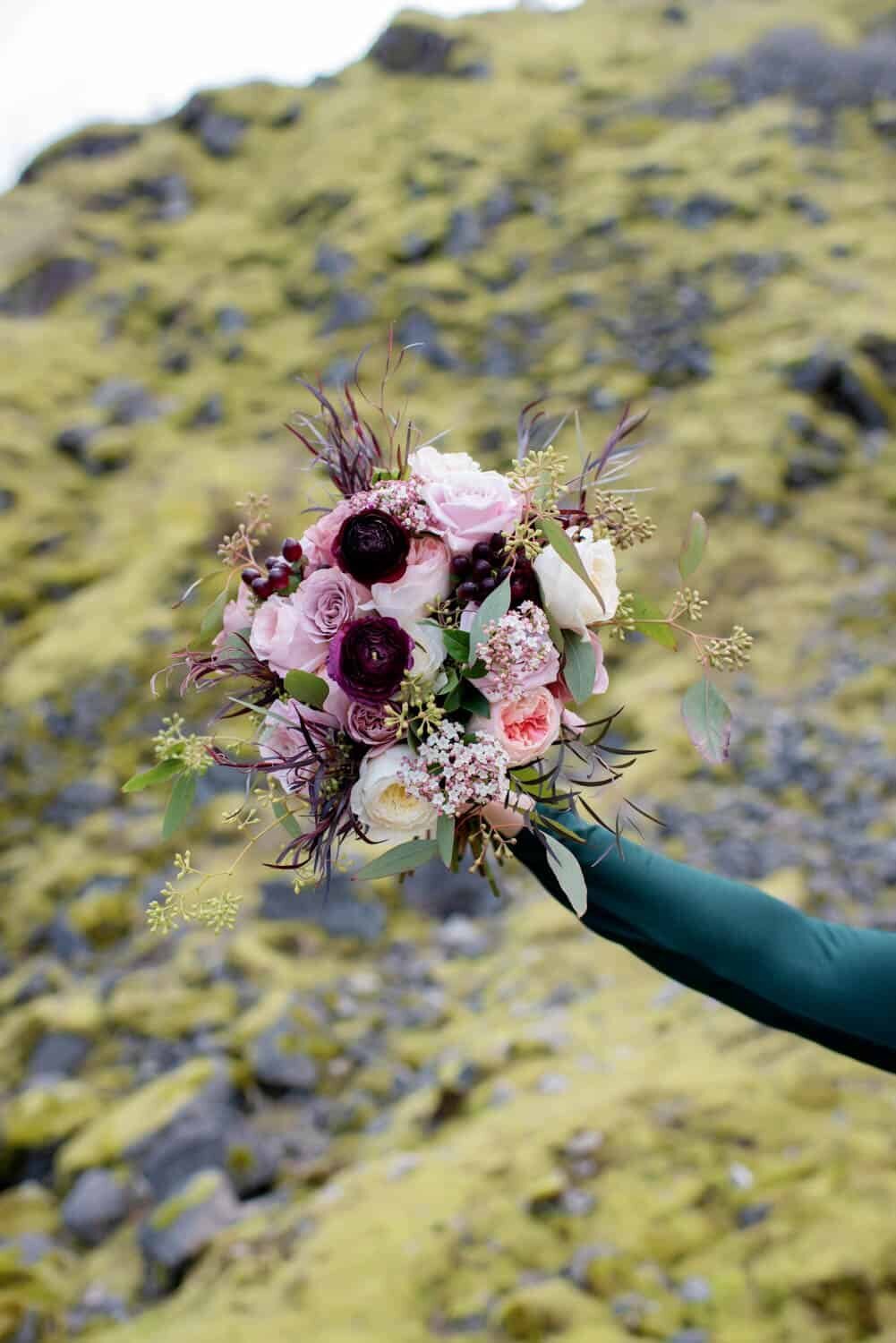 a photo of an extended arm holding a pretty pink and burgundy bouquet by flowers by alana