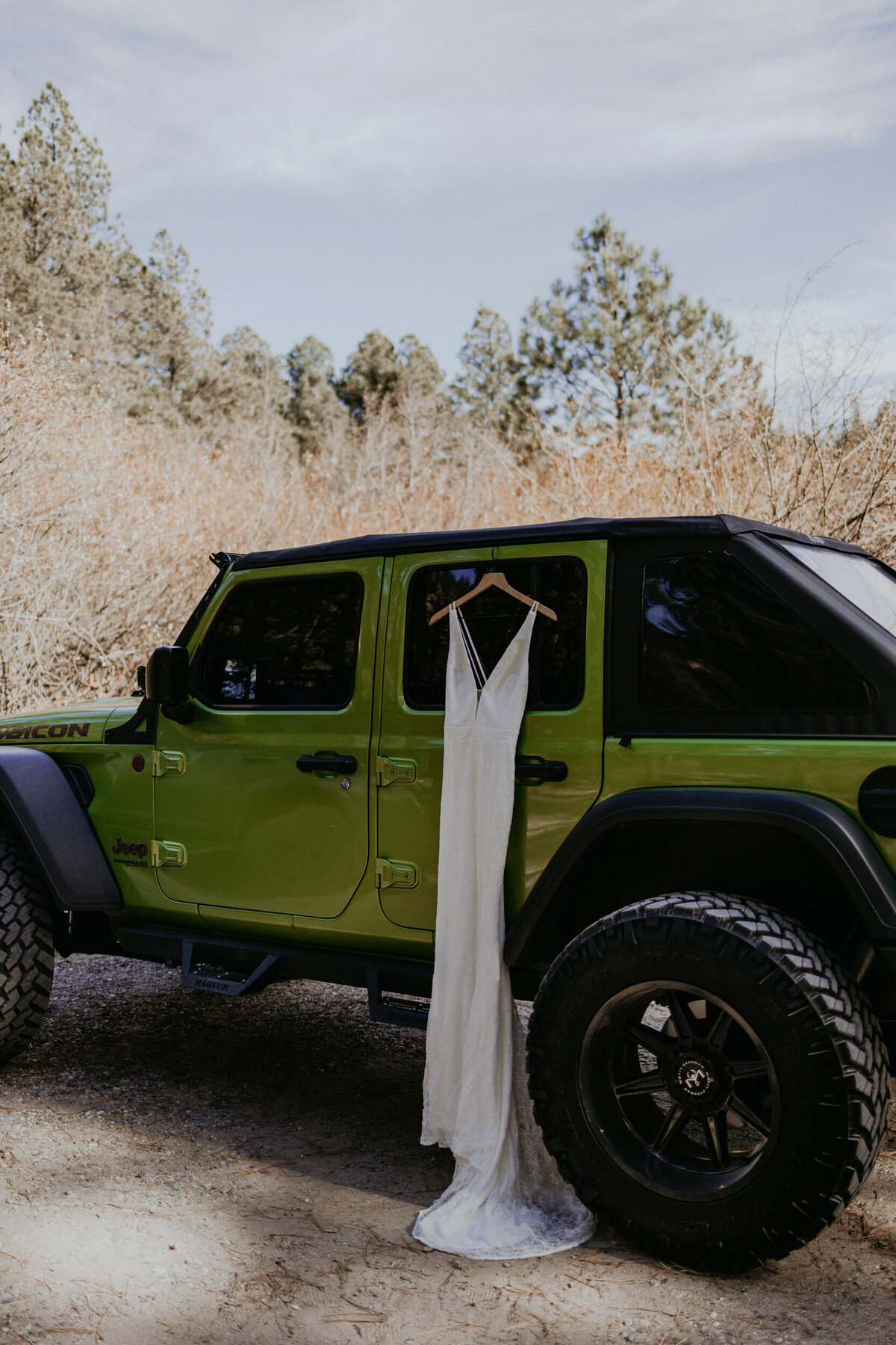 lace wedding dress hanging on green jeep wrangler
