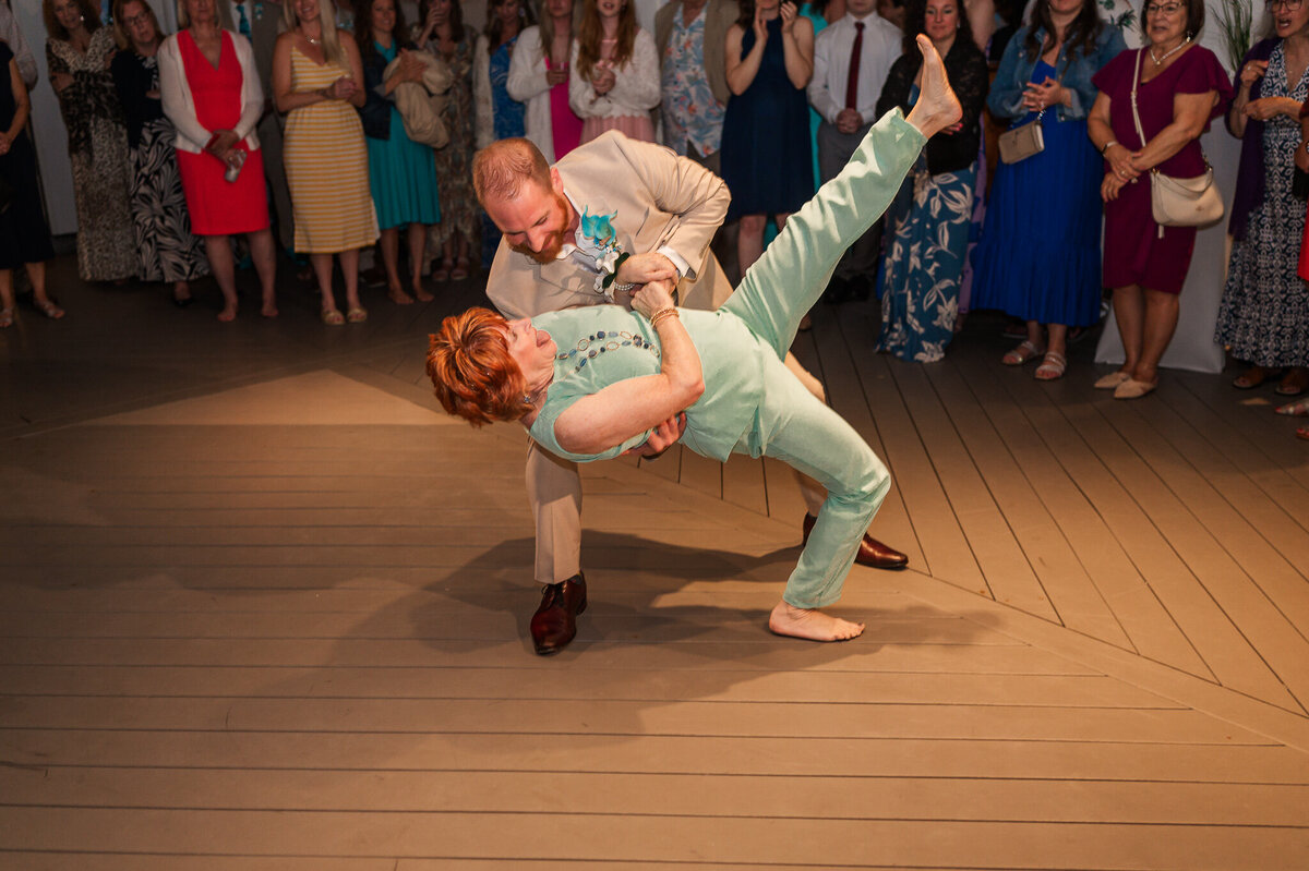 A son dipping his mom on the dance floor during his Wilmington wedding reception by  JoLynn Photography