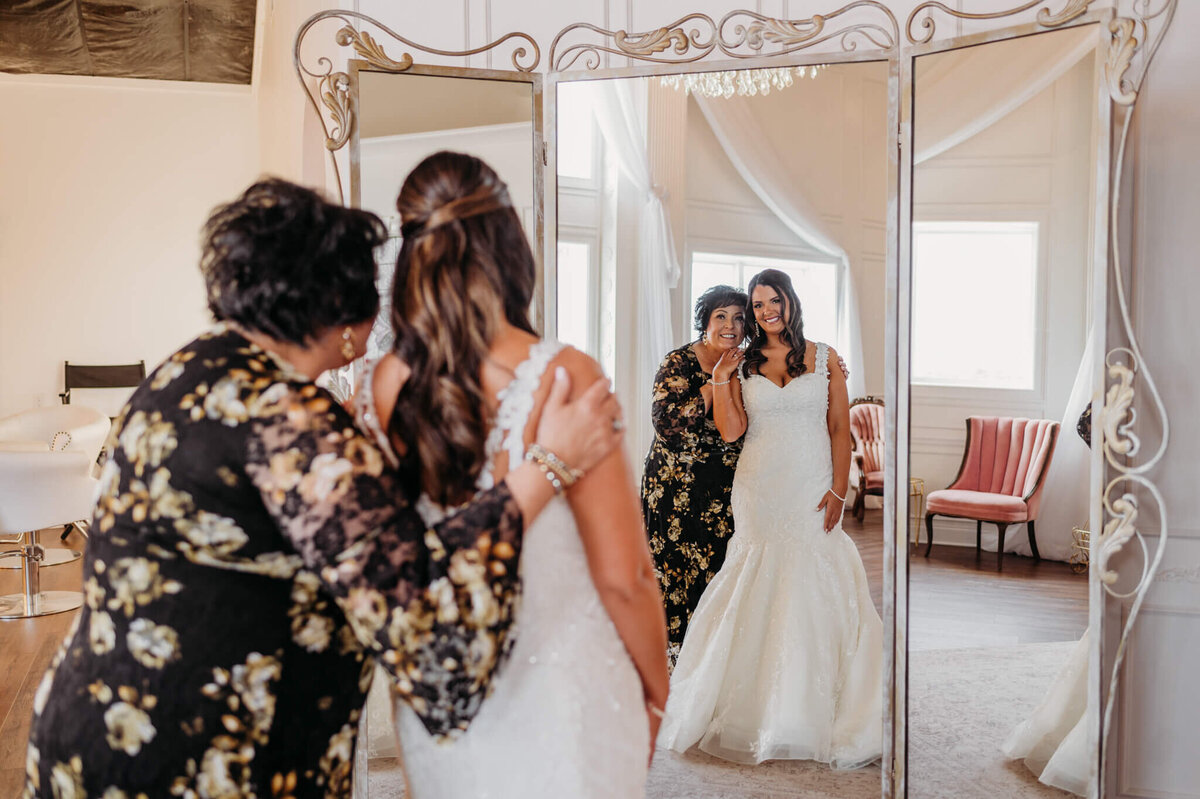 photo Of a bride and her mom hugging and looking into a mirror
