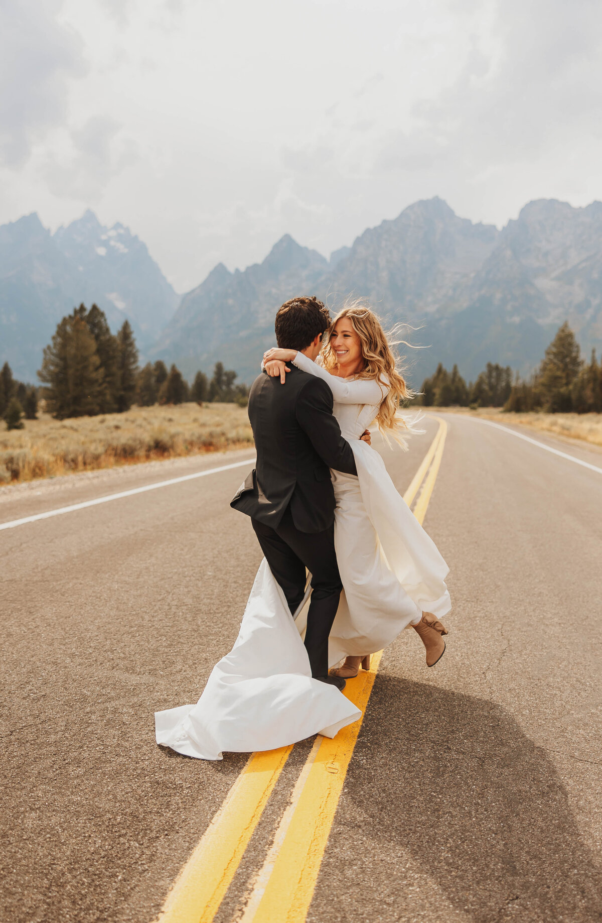 bride and groom embracing in road