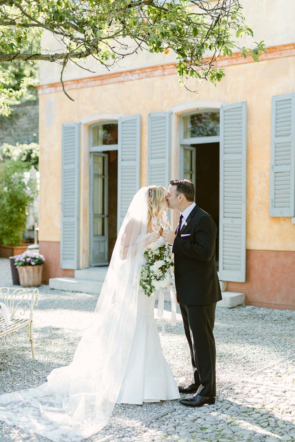 bride and groom kissing in front of villa regina teodolinda