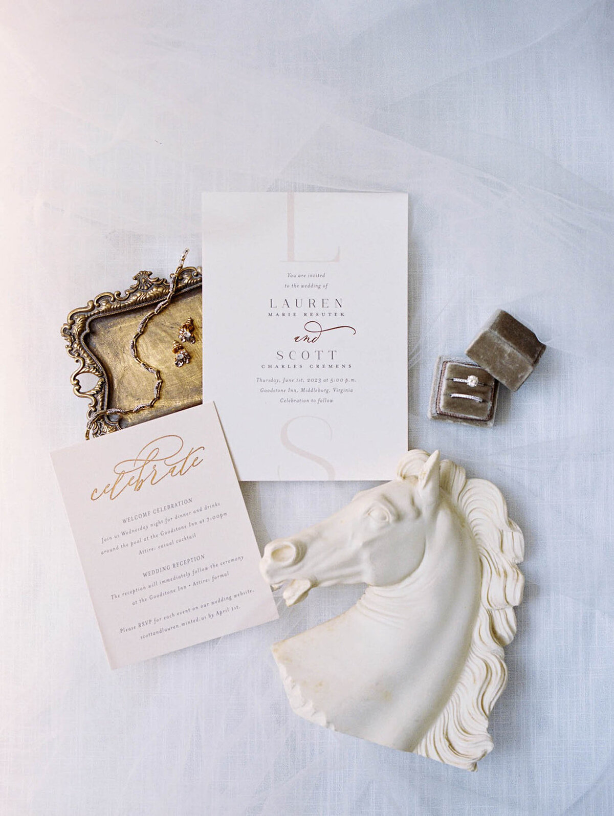 Flat lay of wedding day invitation featuring equestrian touches in gold and white