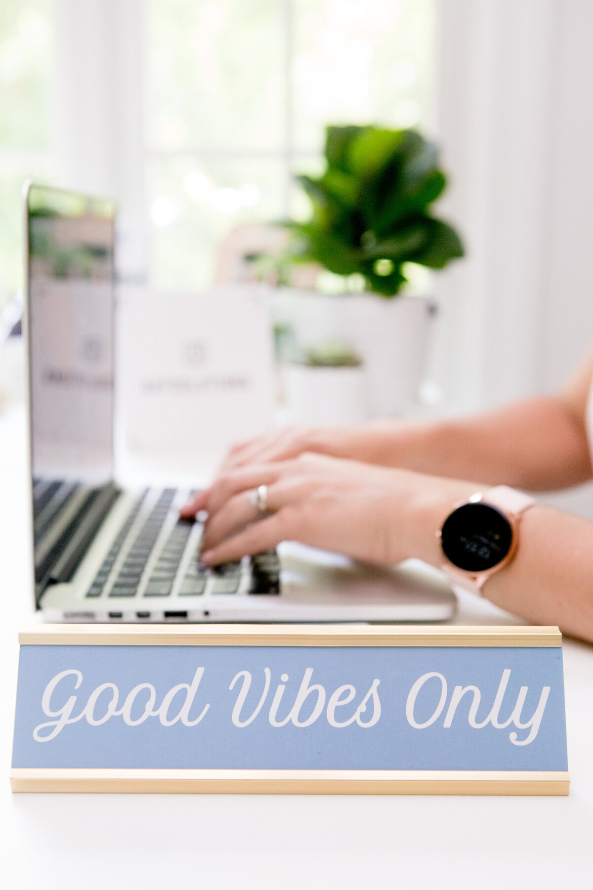 detail shot of woman typing on a laptop with a sign that says good vibes only in the foreground New York branding photographer Milestone Images