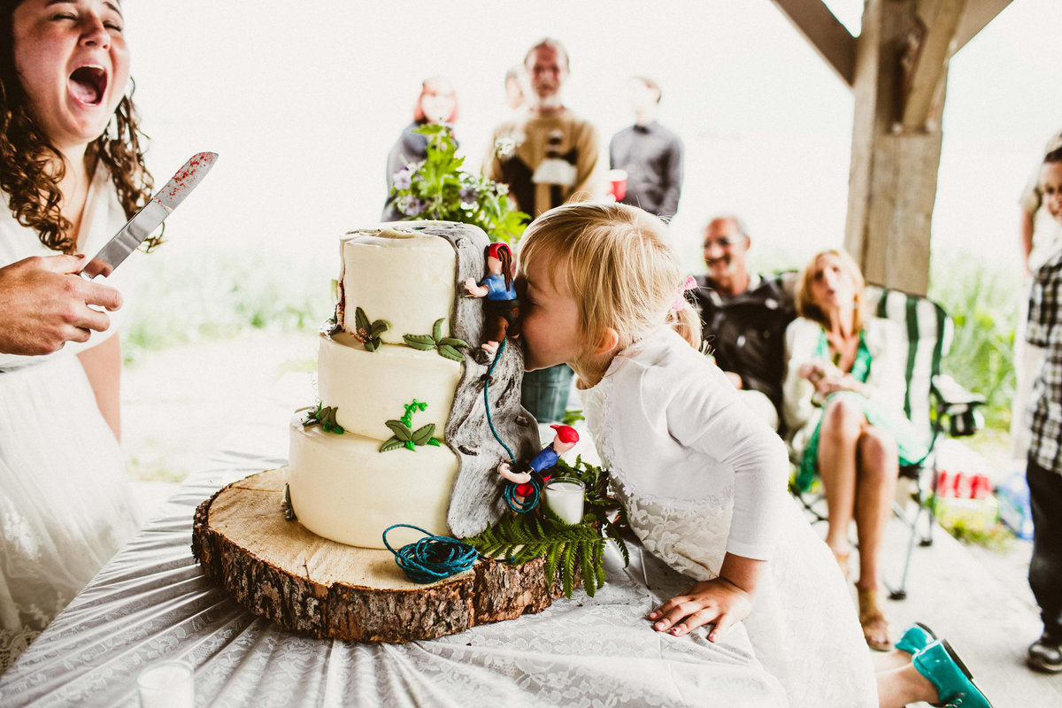 flower girls takes bite of uncut cake in valdez wedding