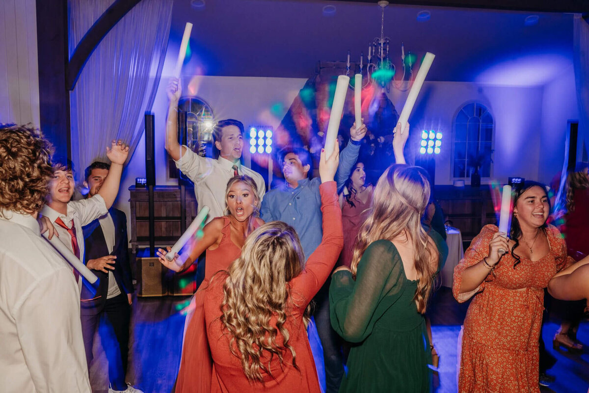 Photo of wedding guests dancing with foam glow sticks