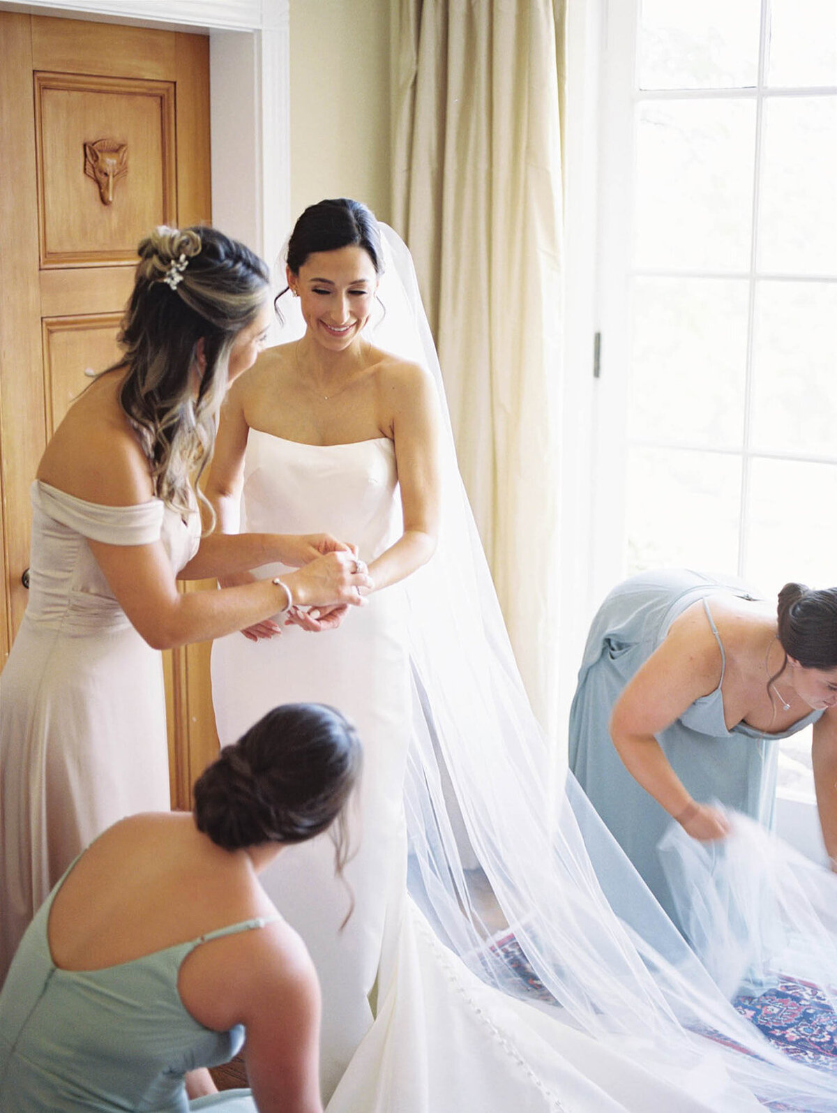 Bride getting ready with bridesmaids helping her
