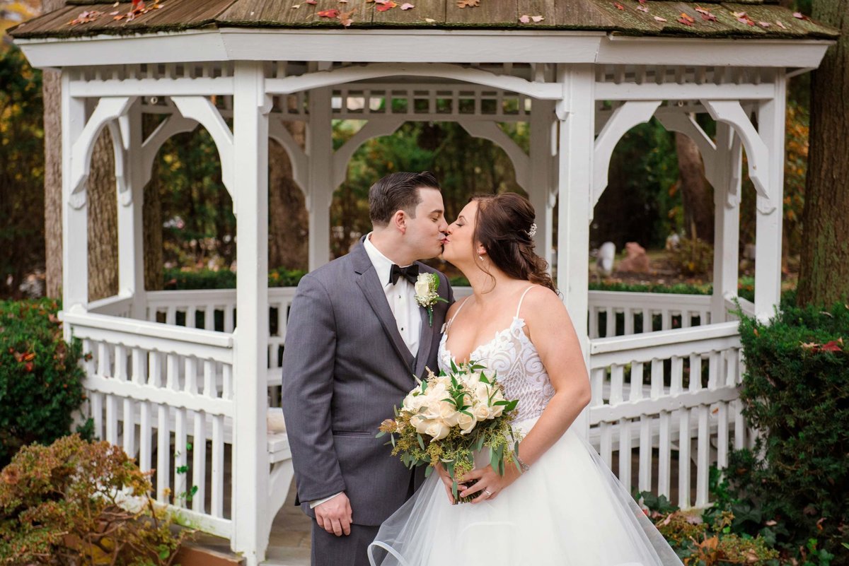 Bride and groom kissing infront of the gazebo of Fox Hollow