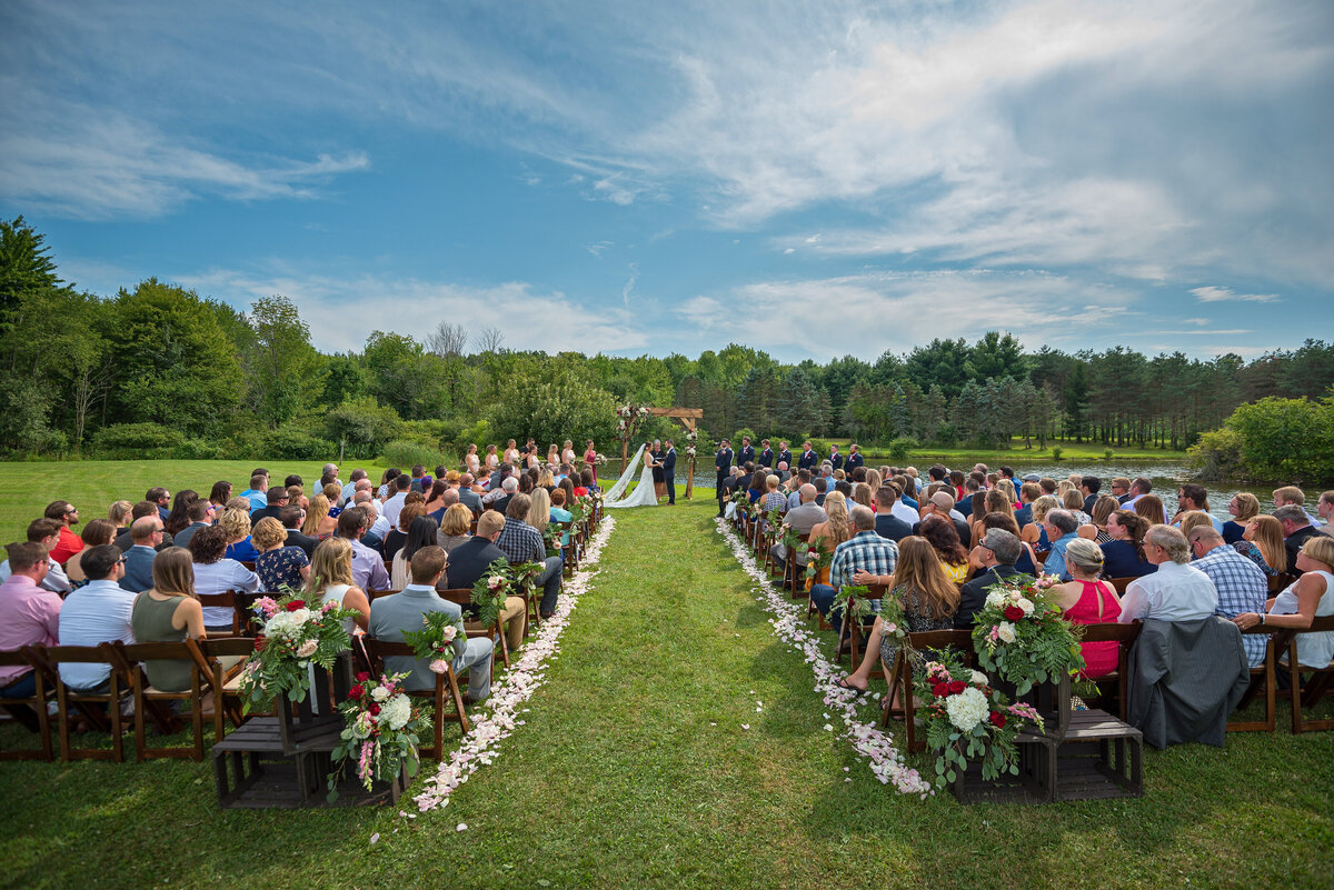Outdoor on location wedding ceremony with green grass and blue skies.