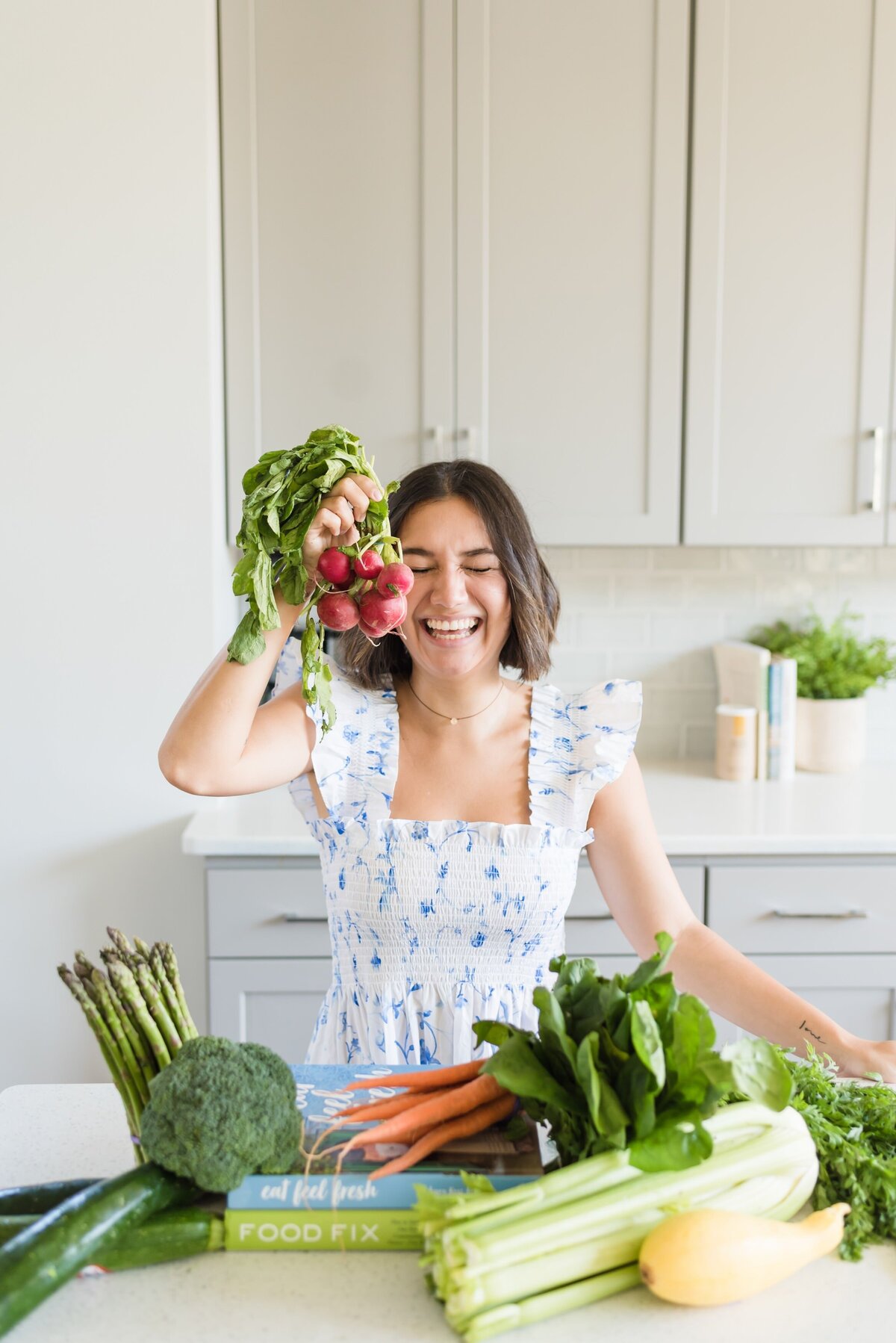 Nutrition and health coach standing at a kitchen counter in a Nashville Airbnb with fruits and vegetables around her