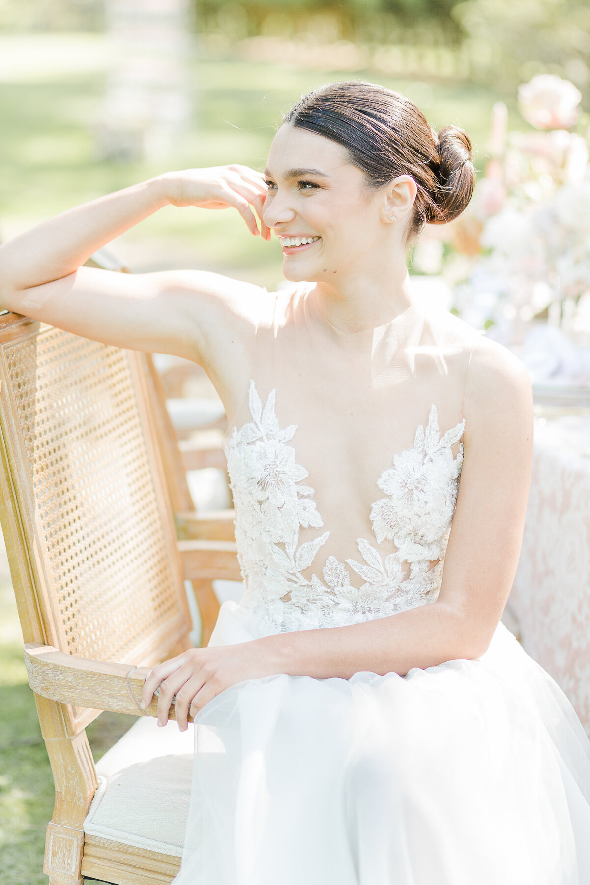 Bride sits in a chair for a casual wedding day portrait. She is looking over her shoulder and off in the distance. Captured by top Rhode Island Wedding Photographer Lia Rose Weddings.