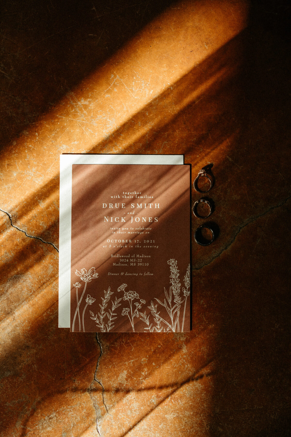 Wedding invitation and rings with fun shadows made by veil and sunlight