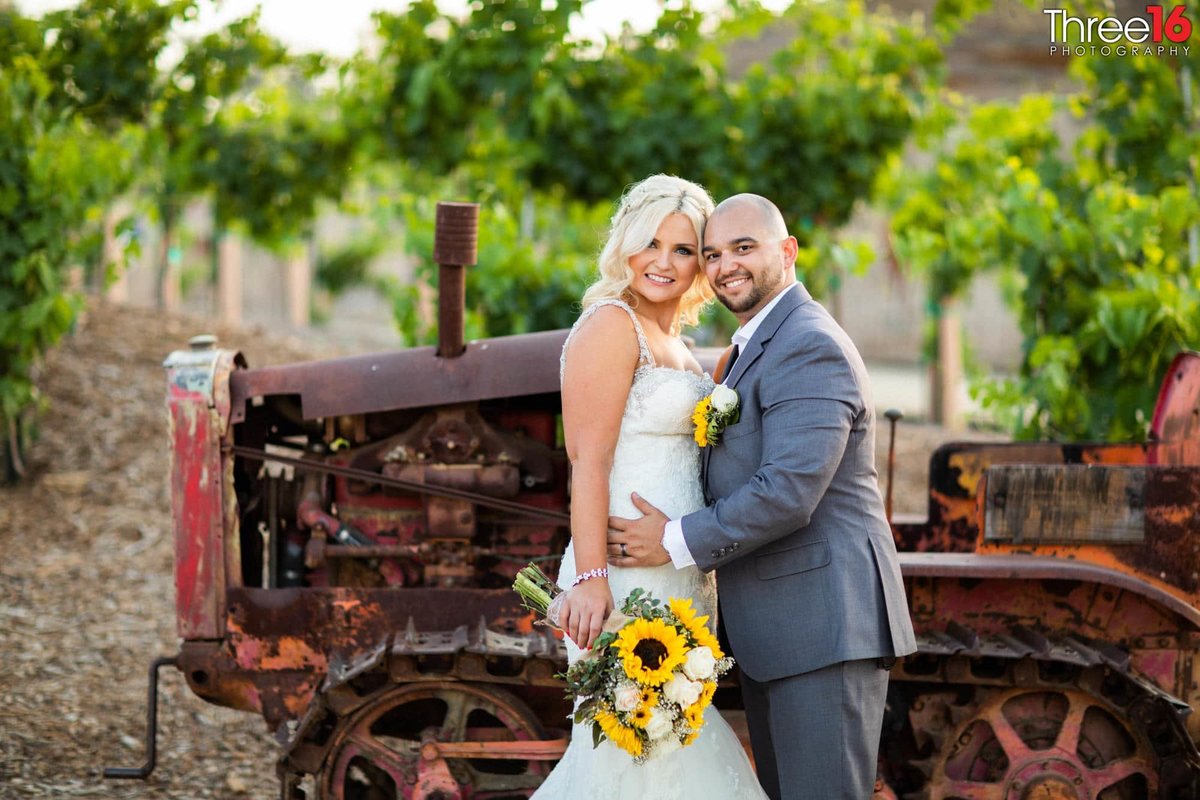 Bride and Groom pose in front of an old tractor