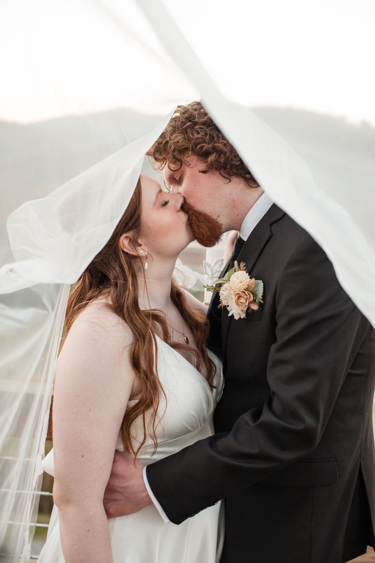 Bride and groom kissing under a veil