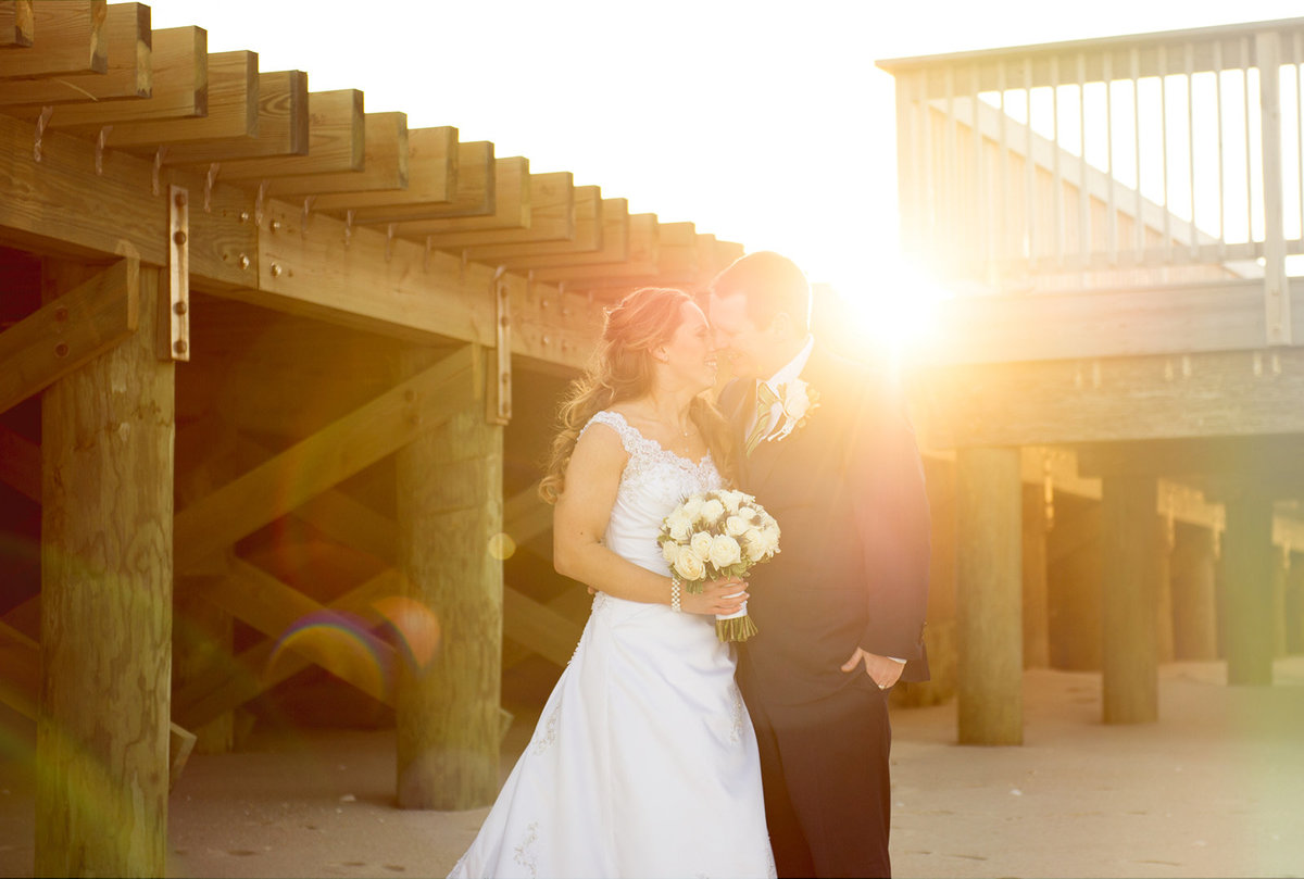 bride and groom with sunflare under boardwalk