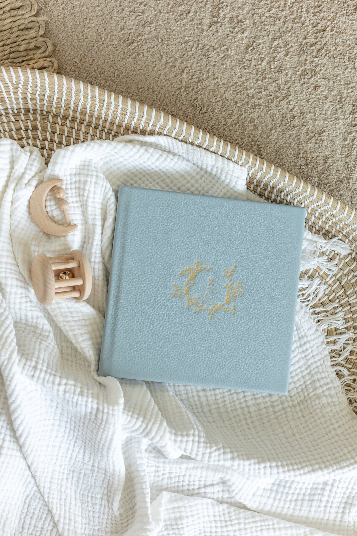 blue leather baby album laid in basket with wooden toys