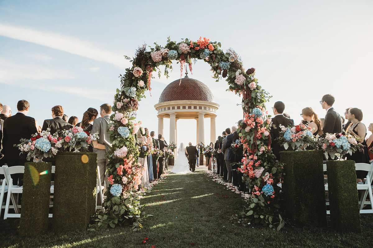 Indianapolis photographer at the Resort at Pelican Hill shooting a gorgeous wedding under a gazebo through a flower arch