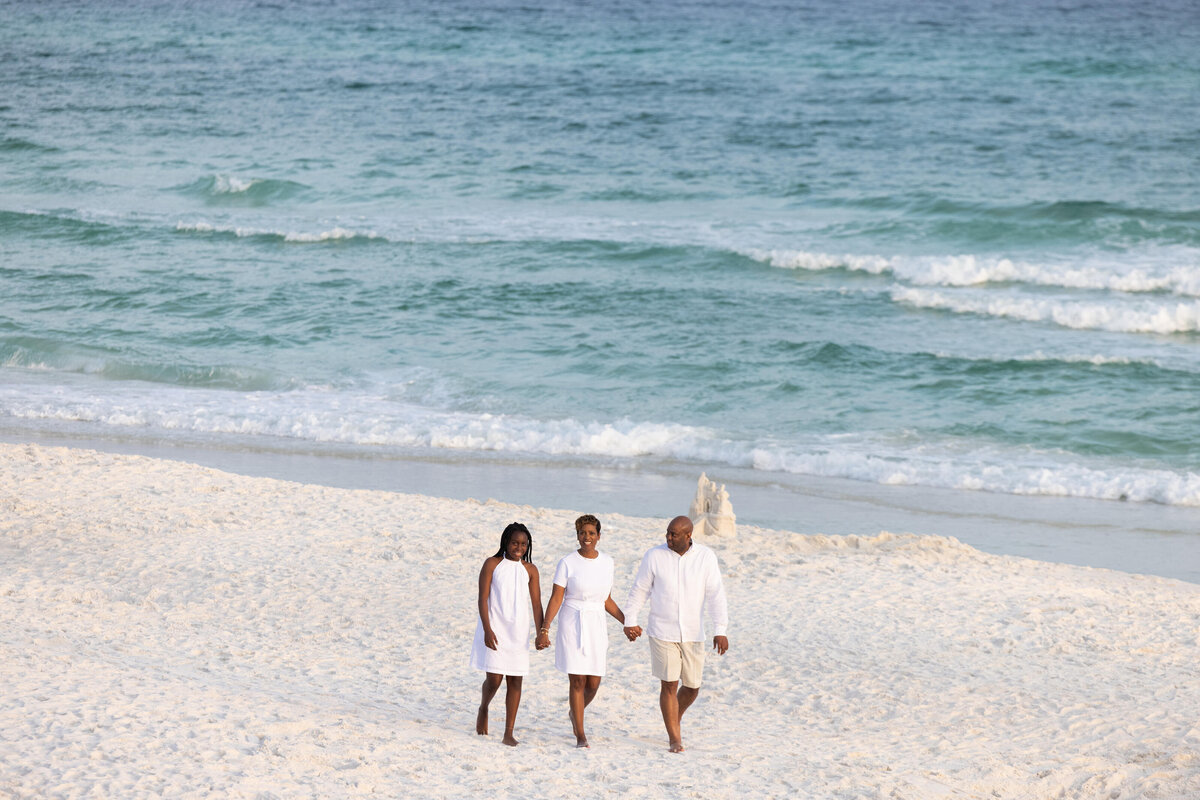 A family holding hands and walking along the beach