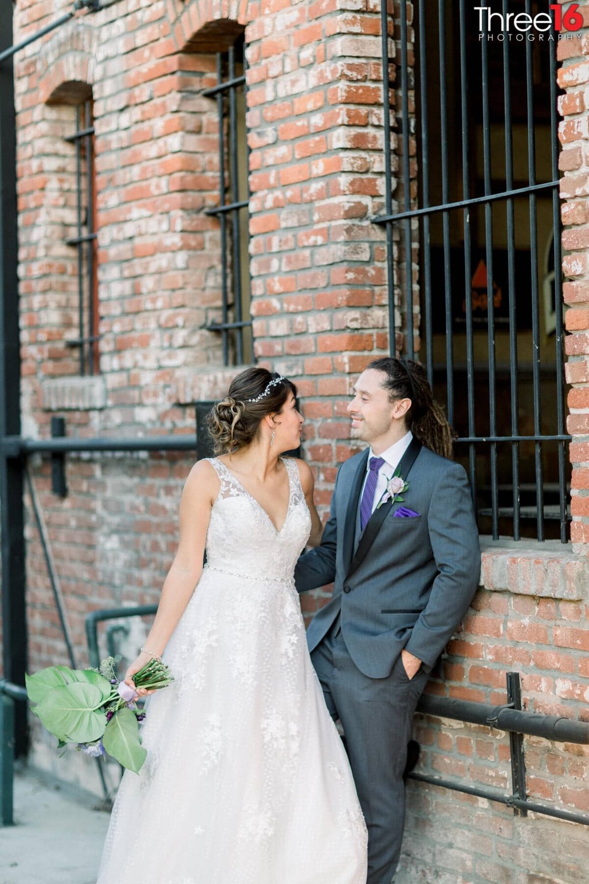 Bride and Groom share a quiet moment together against a brick building