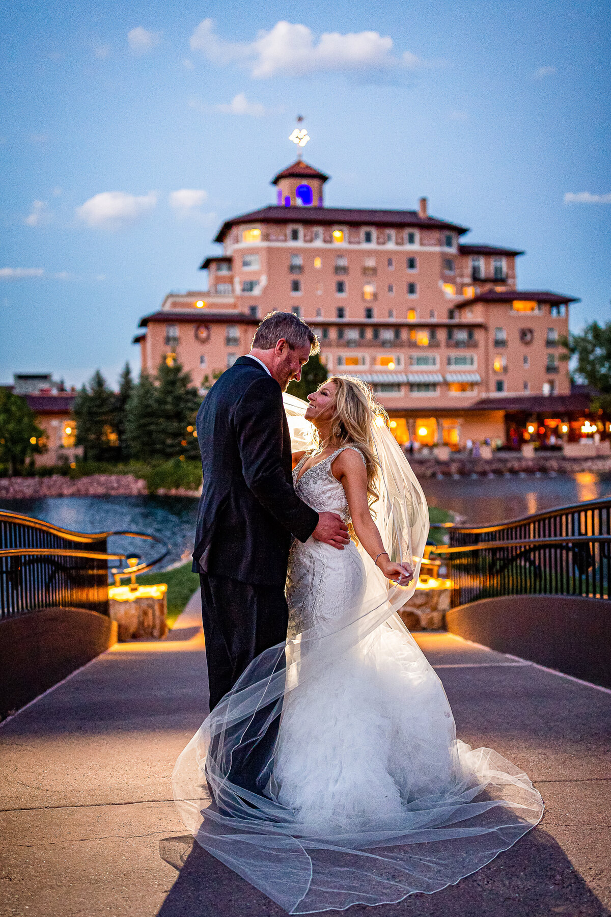 A Bride and Groom Pose on the Broadmoor's Bridge at Dusk