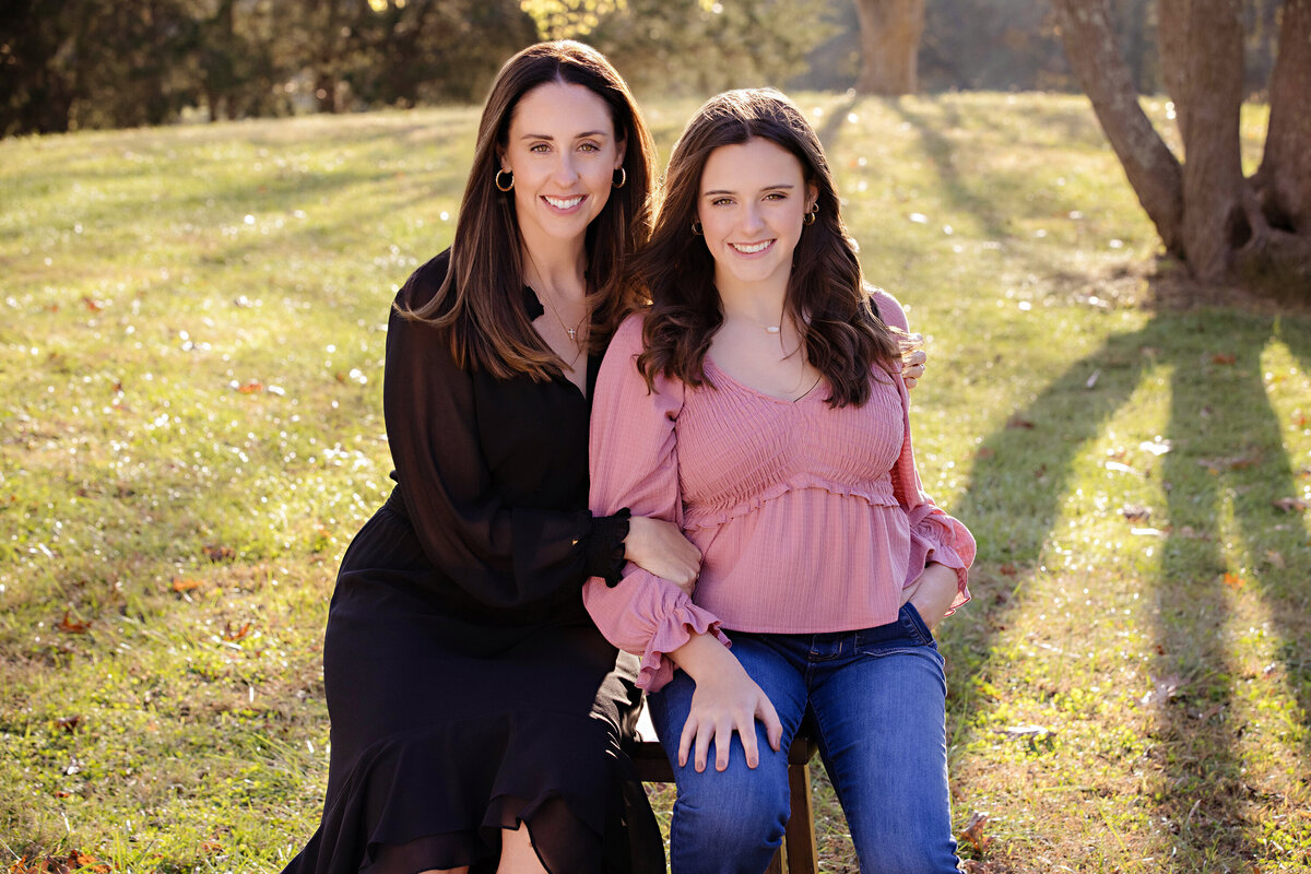Warm portrait of mom with daughter in green field with sloping hill and tree at Anne Springs Close Greenway Charlotte NC