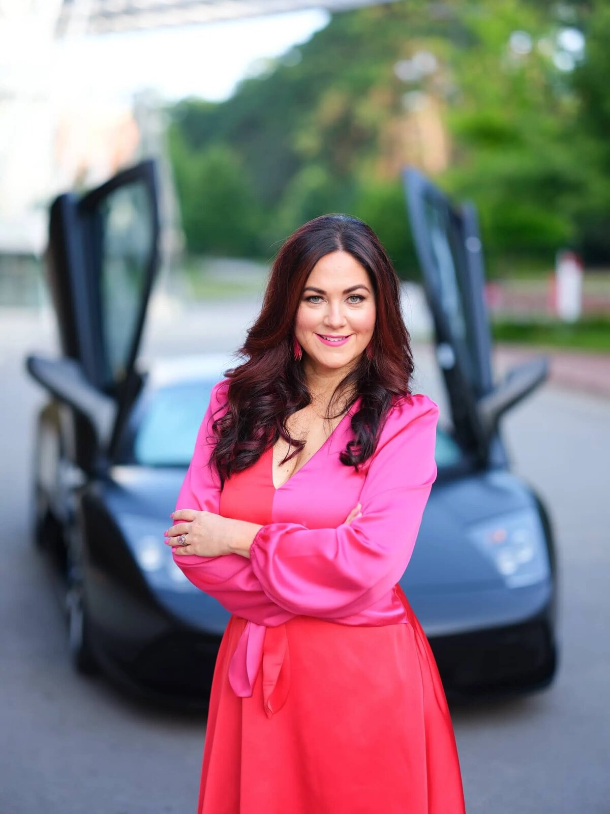 A woman standing in front of a sports car with its doors open