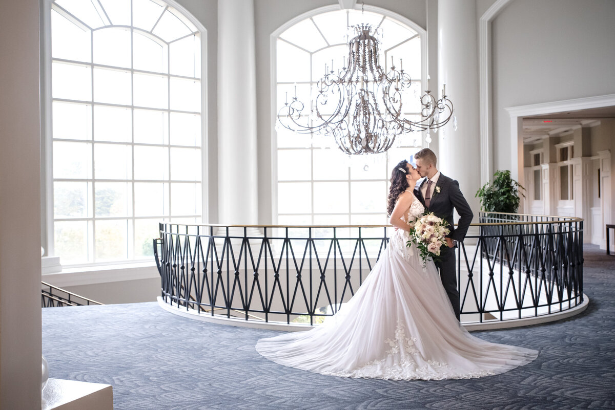 Russian-bride-and-groom-kiss-next-to-chandelier-at-staircase-at-The-Ballantyne-Hotel