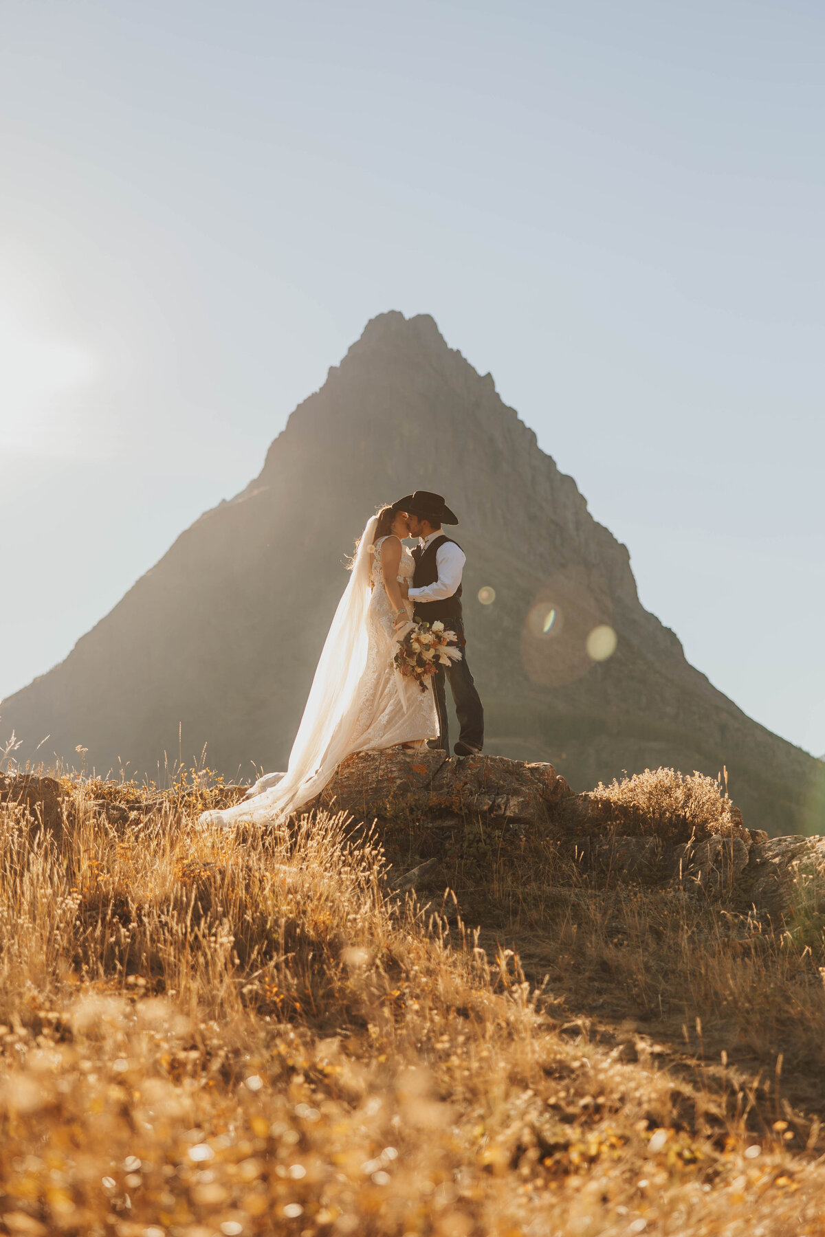 bride and groom kissing on hilltop
