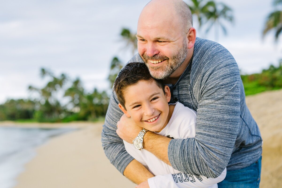 dad and son hugging and laughing at kahala beach