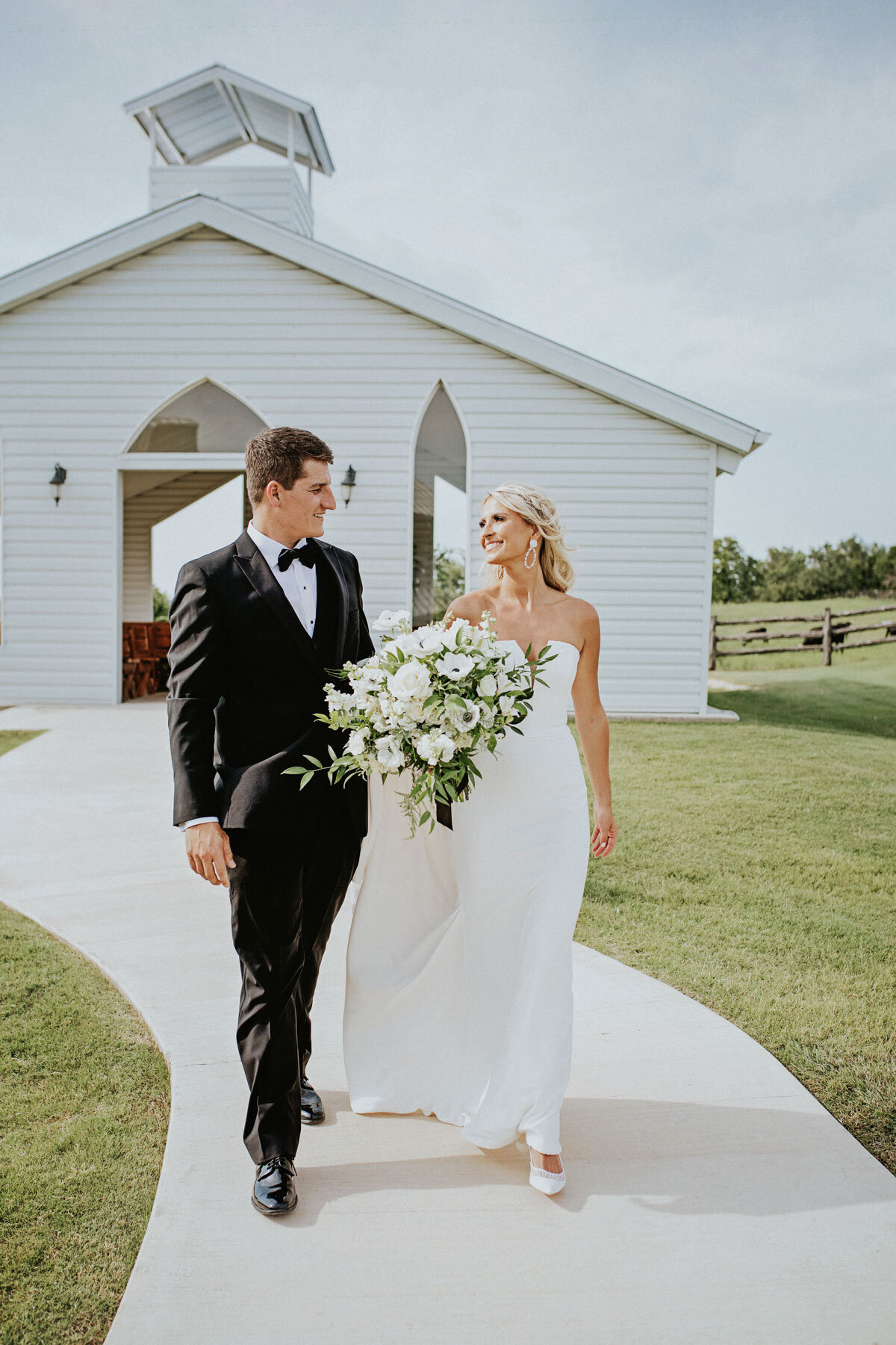 white wedding chapel with bride and groom standing with bouquet