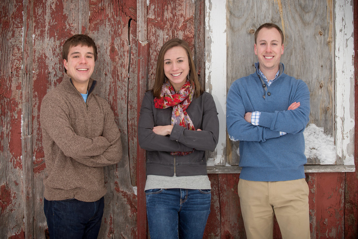 Young adult during winter family portrait in front of a  historic red barn in Leroy Oaks forest preserve