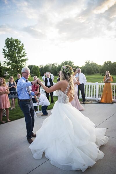 A father of the bride twirls his daughter as the two share a dance at the outdoor wedding reception.