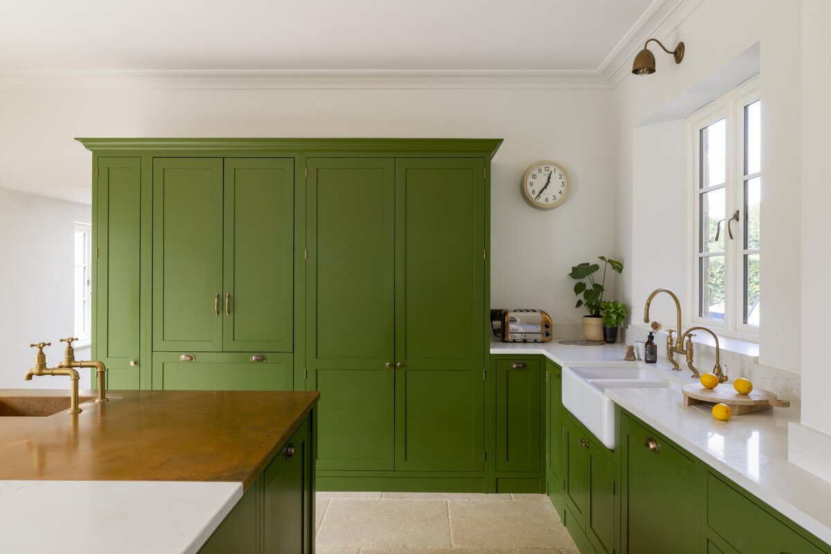 Green kitchen cabinetry with light walls