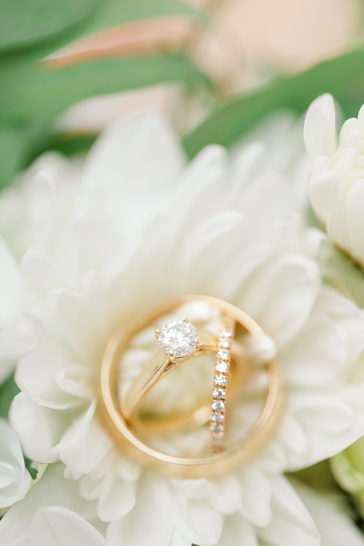Stunning wedding rings layered on each other to form the Trinity shot against a beautiful bridal bouquet