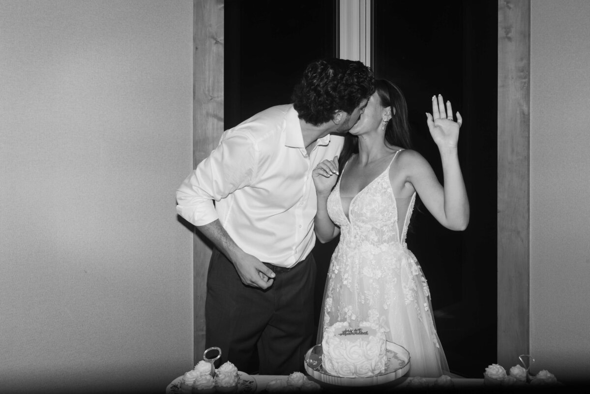 Bride and groom kissing after cutting the cake at Oak Island Resort wedding, Nova Scotia